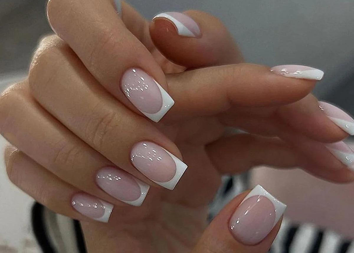 Close-up of hands with pink and white nail polish on a blurred background