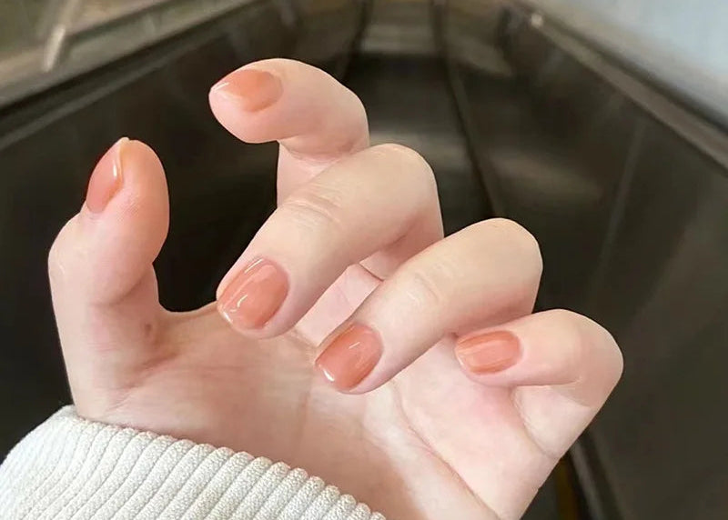 Close-up of a hand with pink nail polish in an indoor setting