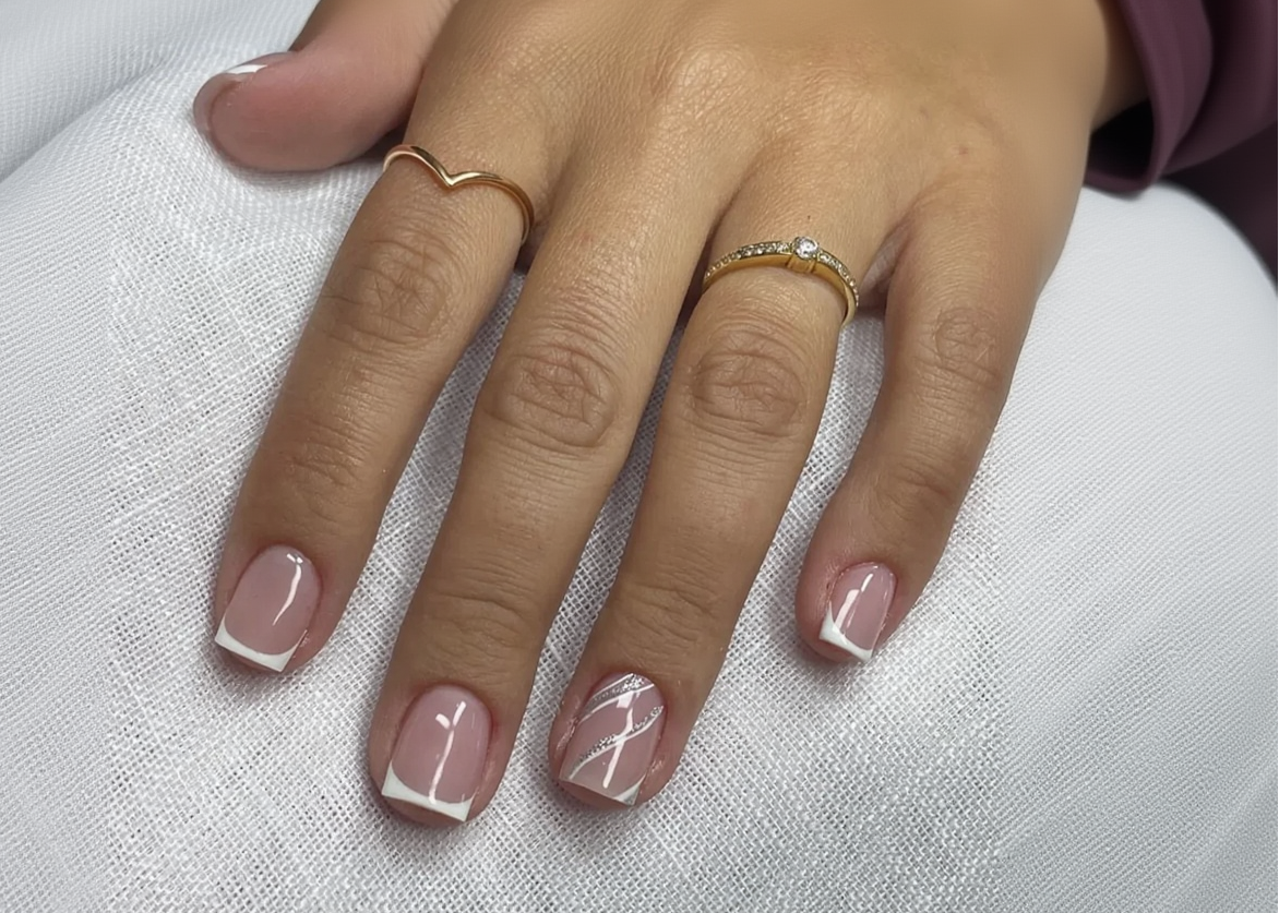 Hand with pink nail polish and gold rings on a white fabric background