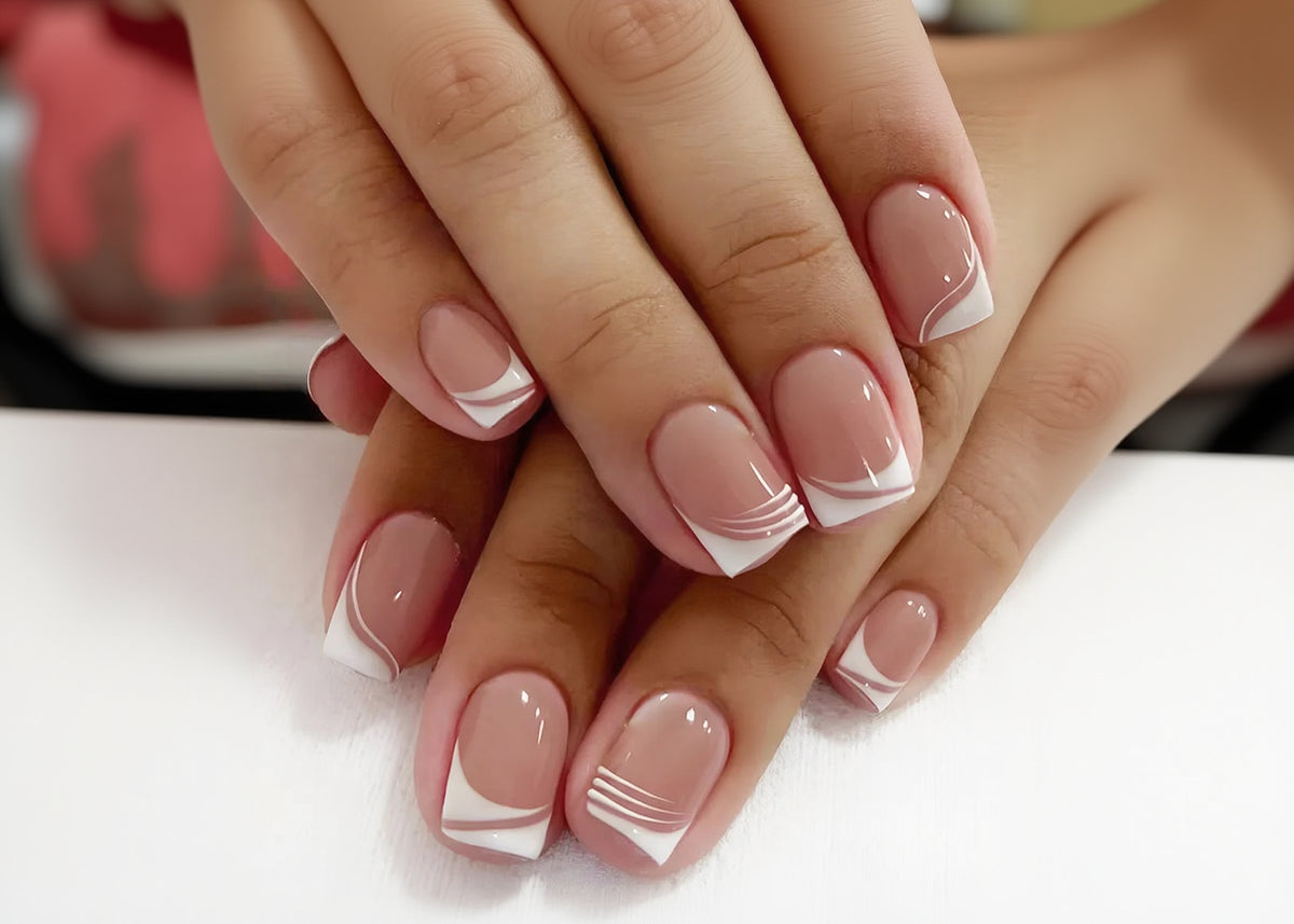 Close-up of hands with pink and white nail design on a light background