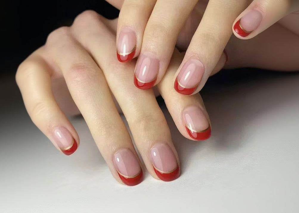 Close-up of hands with red and pink nail polish on a neutral background