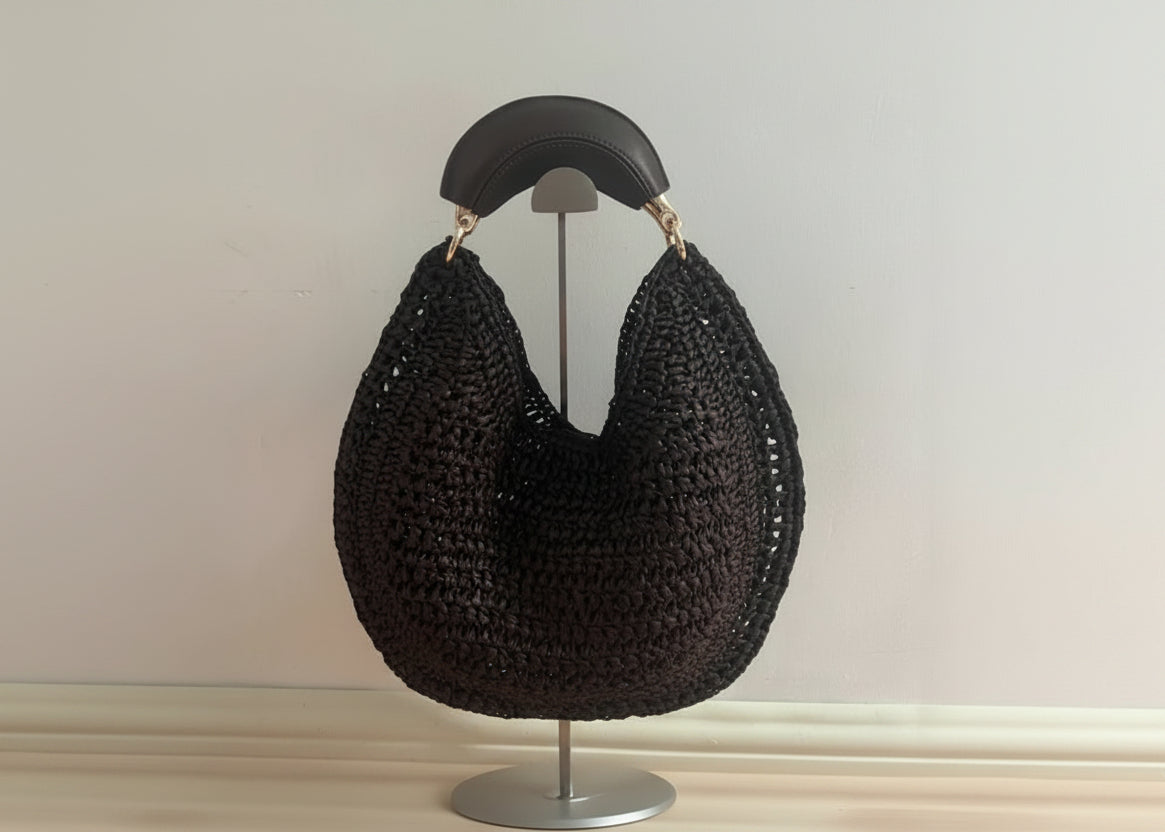 Black woven handbag on a mannequin against a neutral background