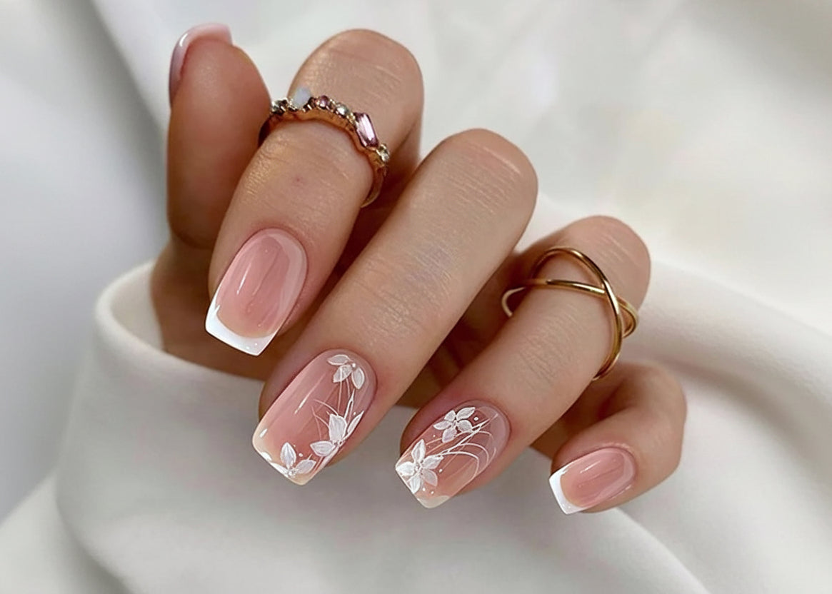 Nails with floral design and gold rings on a white background