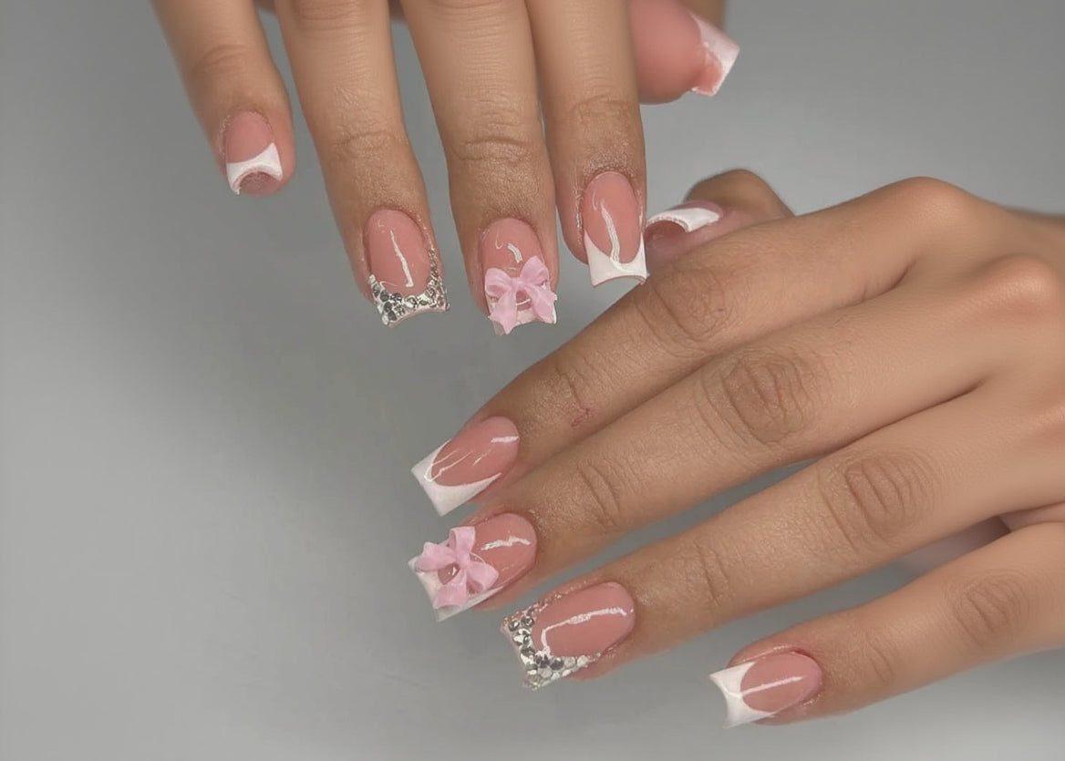 Nails with pink bows and silver decorations on a neutral background