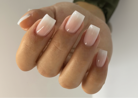 Close-up of a hand with gradient nail polish on a neutral background