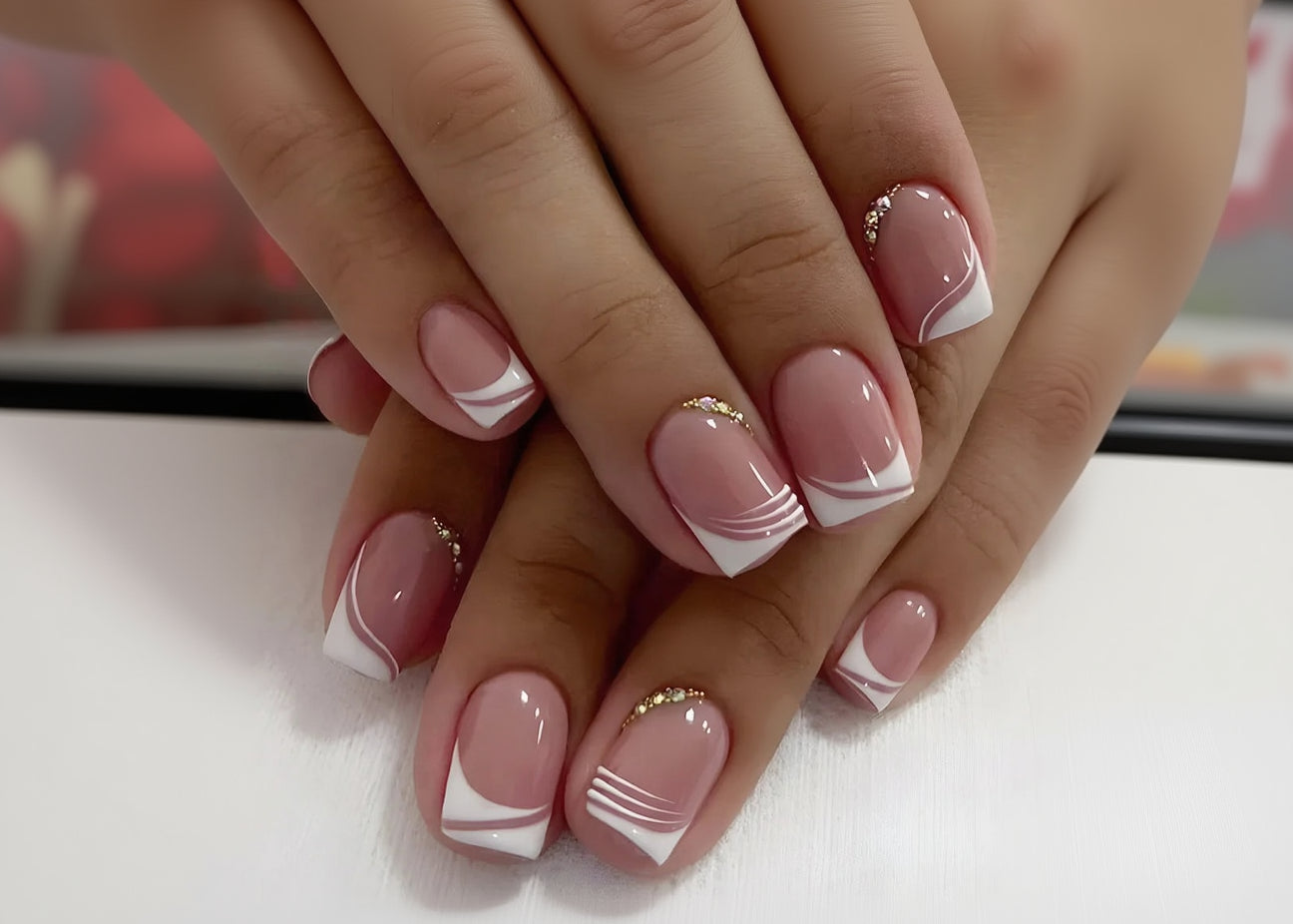 Close-up of hands with pink and white nail design on a light background