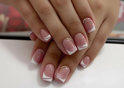 Close-up of hands with pink and white nail design on a light background