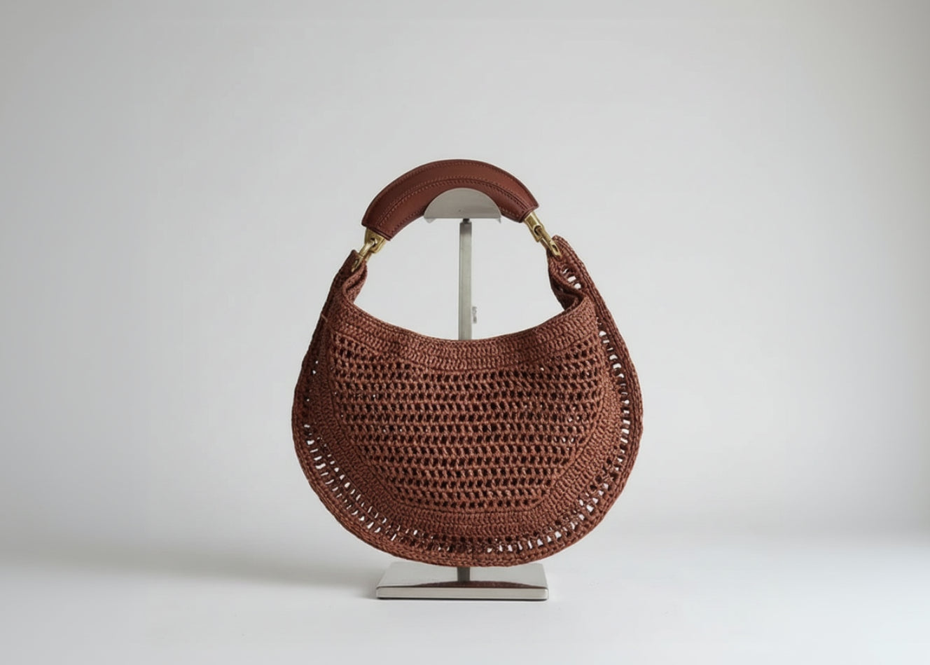 Brown woven handbag on a stand with a decorative background