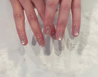 Close-up of hands with glittery nail polish on a textured white background