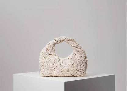 Beige crochet handbag on a white surface with a gray background