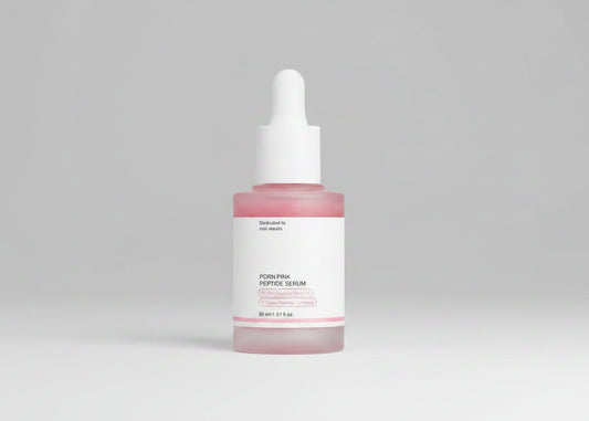 A close-up of a person's face with a dropper bottle of PDRN Pink Peptide Serum overlaid on the left side. A heart-shaped area on the cheek is outlined with a dashed border and the text 'Pores disappear' suggests a skincare result.