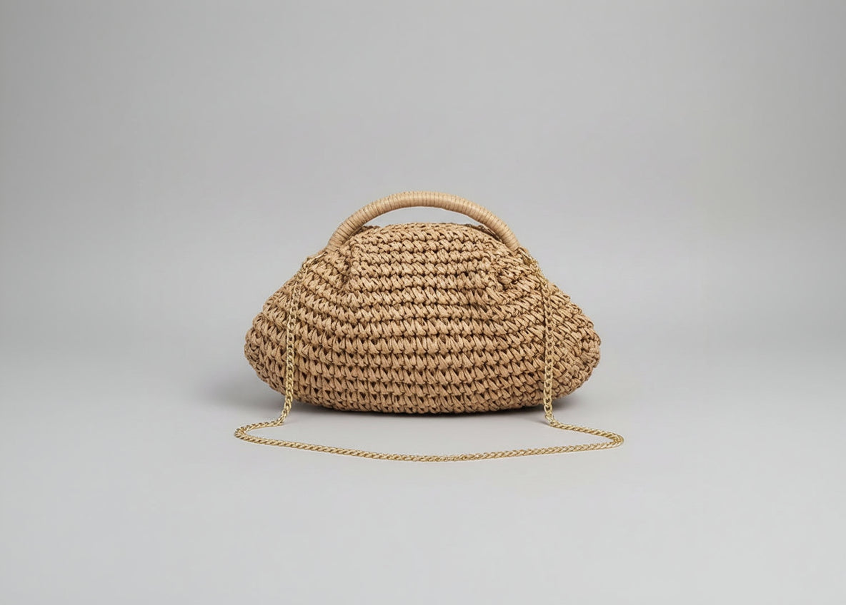 Woven handbag with a chain detail held by a person against a neutral background