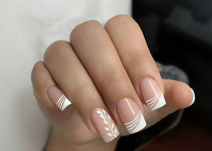 Close-up of a hand with pink nails featuring white decorative patterns.