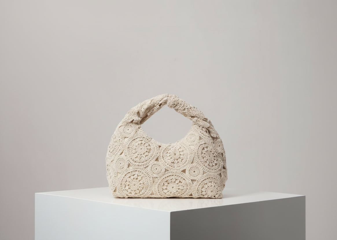 Beige crochet handbag on a white surface with a light gray background