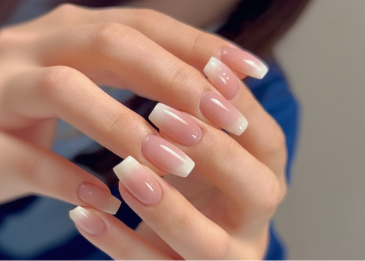 Close-up of a hand with pink and white gradient nail polish.