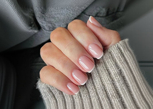 Close-up of a hand with pink nail polish on a textured fabric background