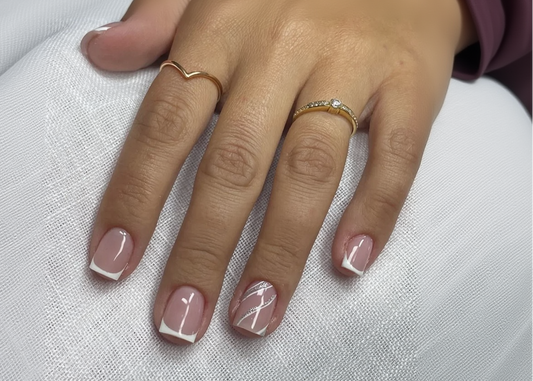 Hand with pink nail polish and gold rings on a white fabric background