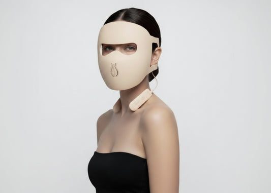 Person wearing a futuristic face mask holding a skincare device on a white background