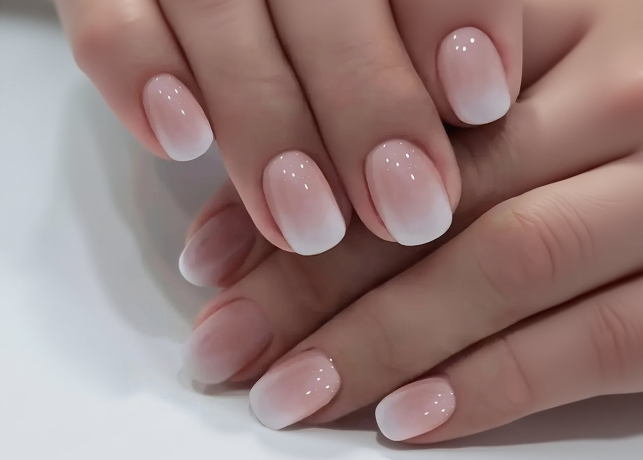 Close-up of hands with pink nail polish on a neutral background