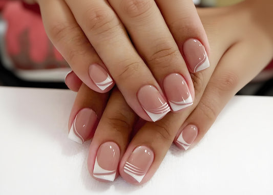 Close-up of hands with pink and white nail design on a light background