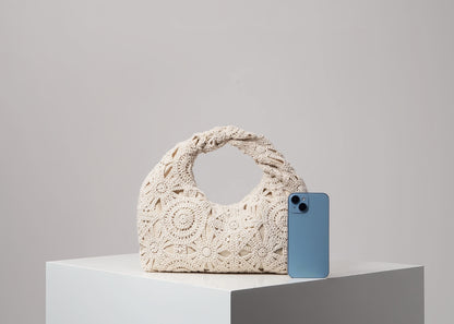 Crocheted handbag next to a smartphone on a light gray background
