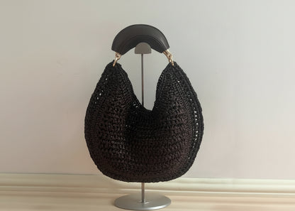Black woven handbag on a mannequin against a neutral background