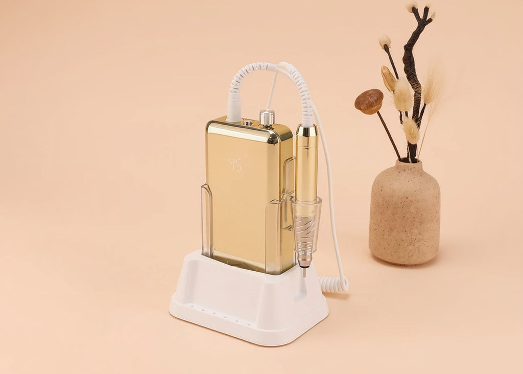 Gold electronic device with white coiled cable on a beige surface with a vase in the corner