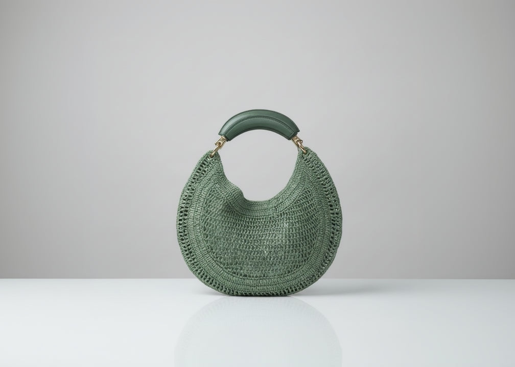 Green woven handbag held by a person with a blurred background
