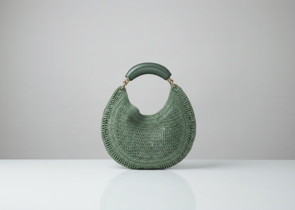 Green woven handbag held by a person with a blurred background