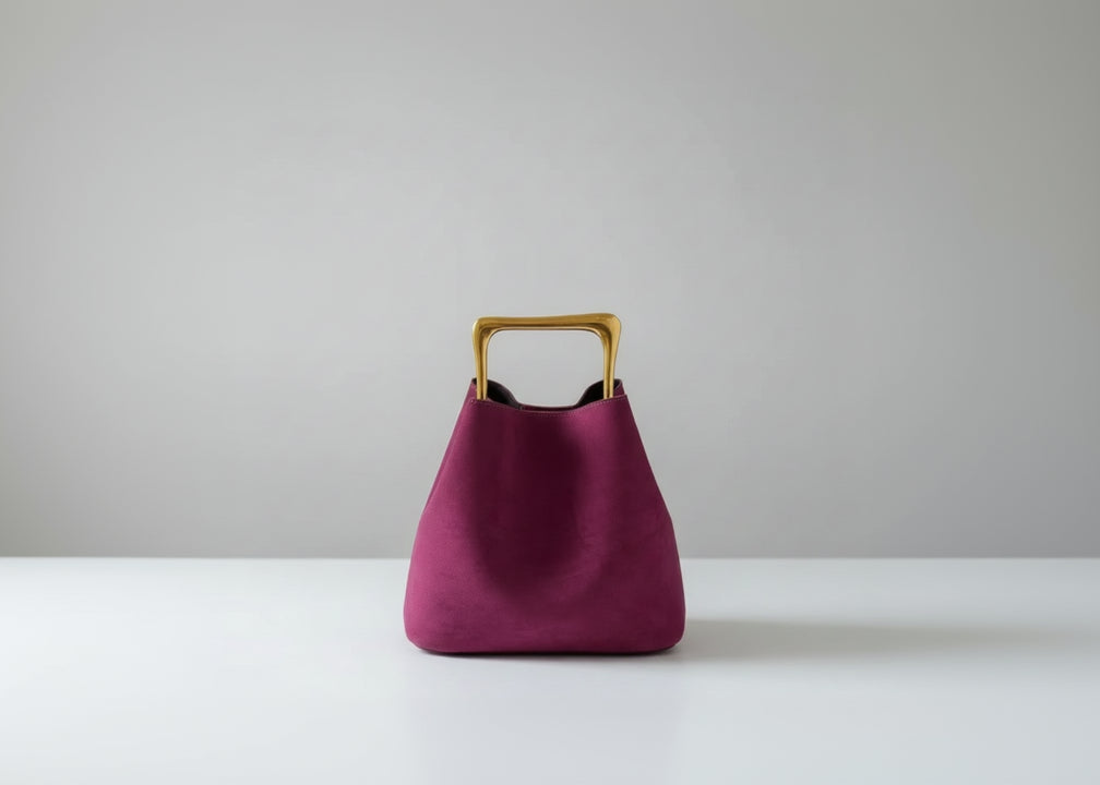 Purple handbag with a gold handle on a wooden surface
