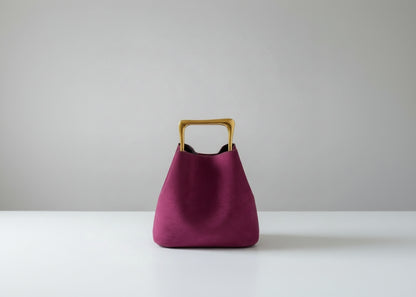 Purple handbag with a gold handle on a wooden surface