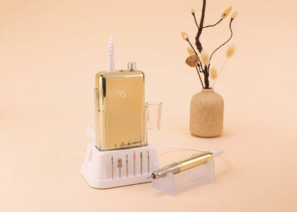 Gold electronic device with digital display on a beige surface with a vase and branches.