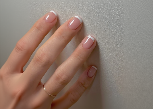 Hand with pink nail polish on a plain background